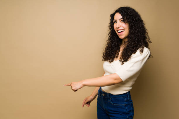 istock Excited latin woman pointing to copy space 1455374717