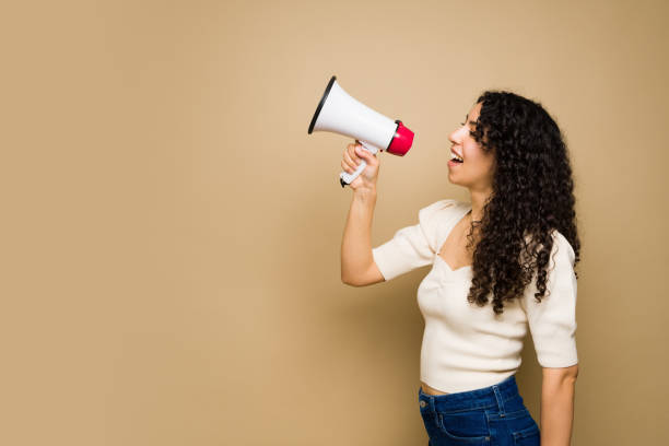 istock Cheerful latin woman shouting with a megaphone 1455374744