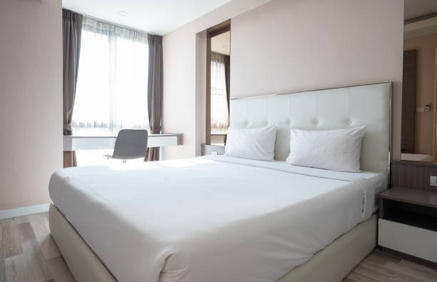 Comfortable bed without guest in hotel bedroom.