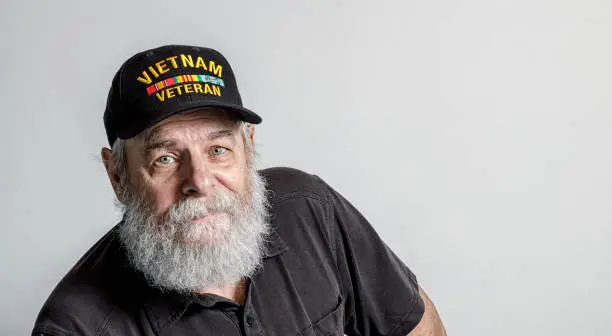 Portrait of a real life, real person senior adult man United States Navy USA Vietnam War military veteran. He's wearing a commemorative Vietnam War Veteran's baseball cap style hat.
