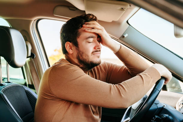 accroché au volant, fermant les yeux et s’appuyant sur la main du conducteur, l’homme se repose dans la voiture. - overworked worried distraught front view photos et images de collection