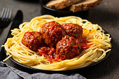 Traditional Italian meatballs in tomato sauce on black plate.Close up of detail.