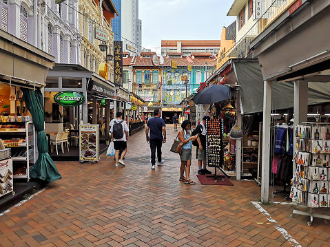 People walking at the Chinatown street market in downtown Singapore, lined with restaurants and souvenir shops.