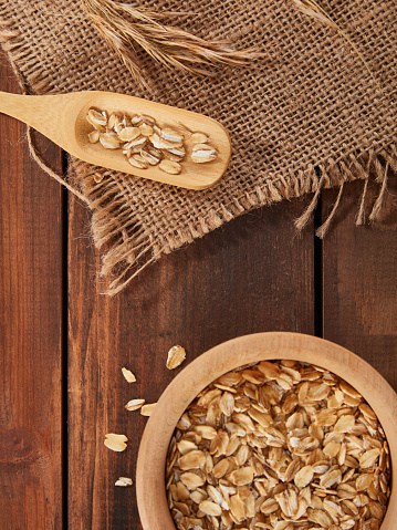 Oat Flakes in Bowl With Spoon Over Wood Background