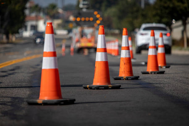 coni stradali su strada con freccia elettronica che punta a destra per deviare il traffico e auto bianca in lontananza - road construction immagine foto e immagini stock