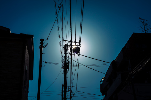 A utility pole photographed backlit in downtown Tokyo.