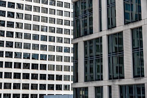 The facades of two skyscrapers having differing architectural features shot full frame as an abstract corporate background.