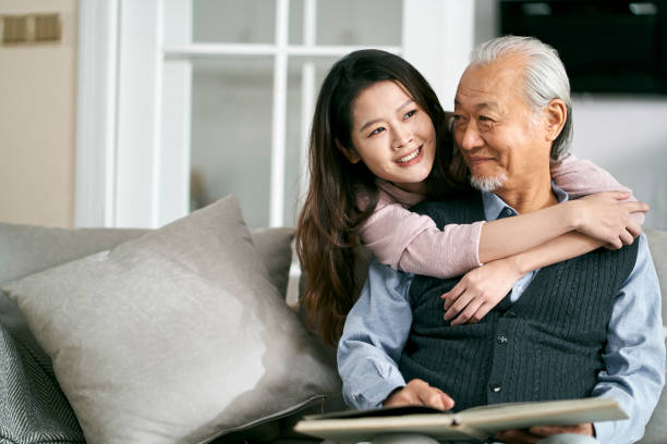 elderly asian father and adult daughter conversing at home stock photo