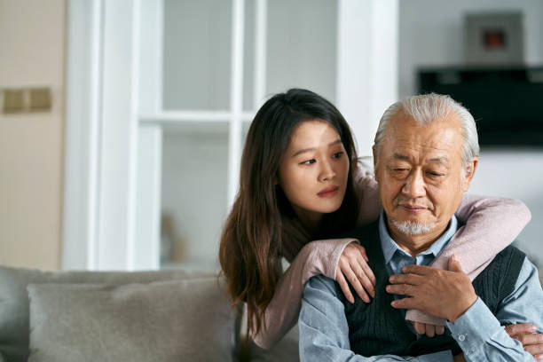 young asian adult daughter conforting senior father at home - senior adult with daughter father imagens e fotografias de stock