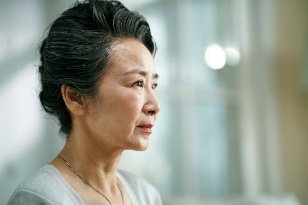 head shot portrait of a sad asian senior woman stock photo