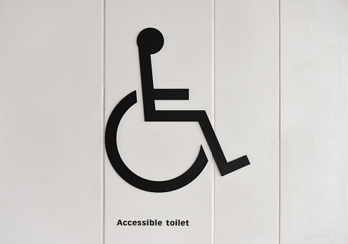 Close-up of persons with disabilities restroom sign on the wall.