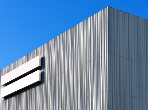 Close-up of two blank billboards on white vertical striped concrete wall building.