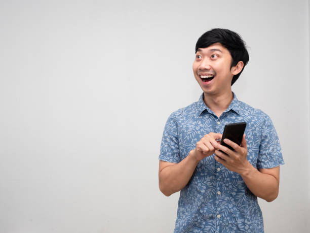 istock Positive asian man blue shirt using mobile phone with happiness smile looking at copy space isolated 1455403667