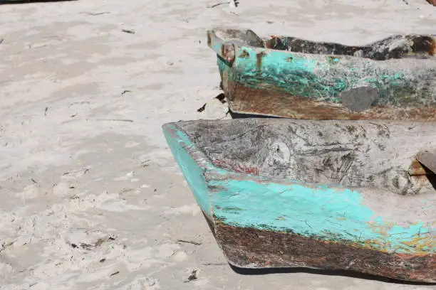 Two old turquoise color wood boats on a white sand beach