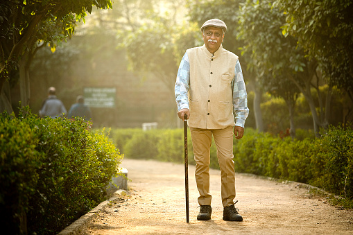Smiling senior man with walking stick enjoying his day at park