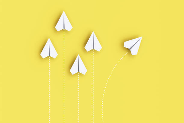 istock Paper planes on a line and one is leading, isolated on yellow background, concept teamwork, leadership and management. 1455407954