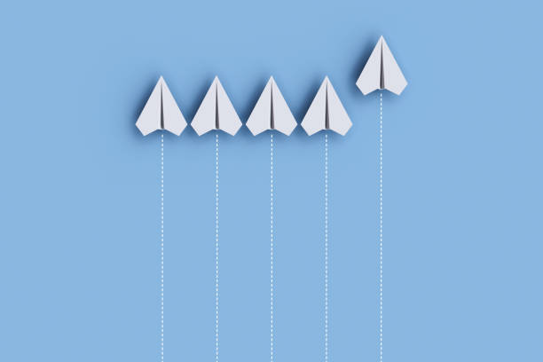 istock Paper planes on a line and one is leading, isolated on blue background, concept teamwork, leadership and management. 1455407956