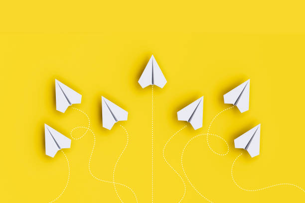 istock Paper planes on a line and one is leading, isolated on yellow background, concept teamwork, leadership and management. 1455407957
