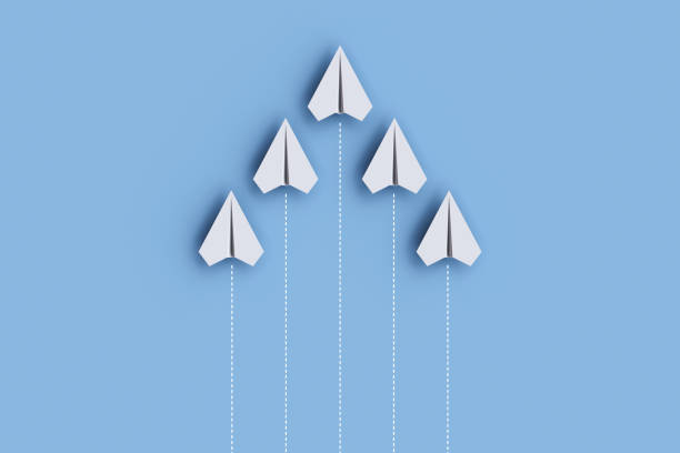 istock Paper planes on a line and one is leading, isolated on blue background, concept teamwork, leadership and management. 1455407958