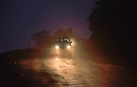 A car with headlights on moving in the dark.