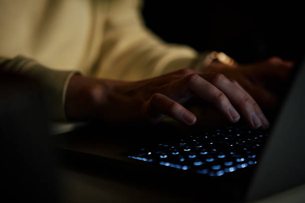 istock Anonymous woman working on laptop at night 1455409840