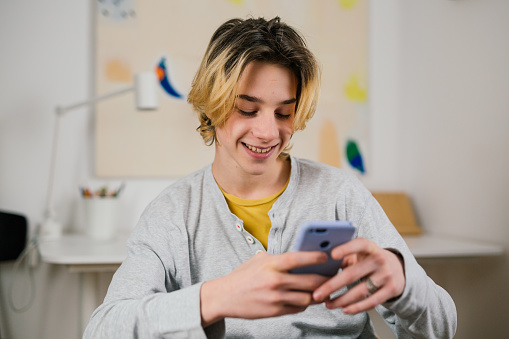 smiling teenage boy texting on mobile phone