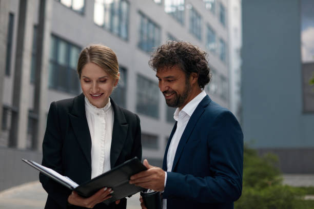 istock Young Positive Man and Woman Holding Clipboard with Documents 1455414498