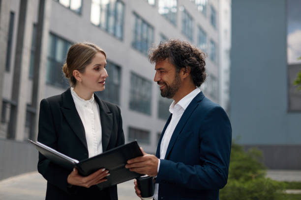 istock Business Couple Outdoors Examining Documents. People Discussing Project 1455414501