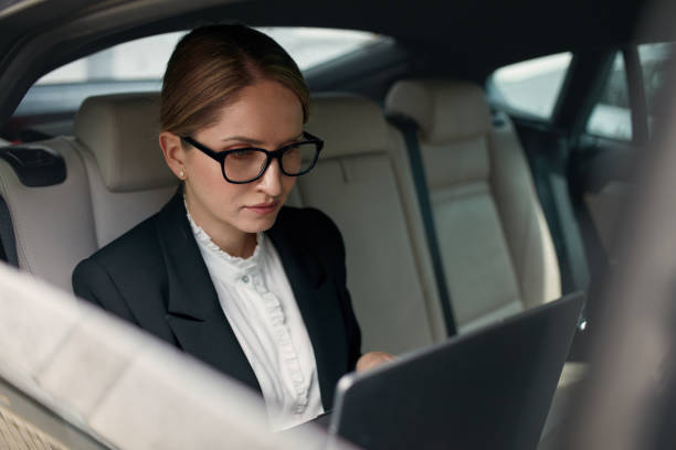 poważna skoncentrowana kobieta biznesu 60-65 lat korzystania z laptopa w samochodzie - 60 65 years zdjęcia i obrazy z banku zdjęć