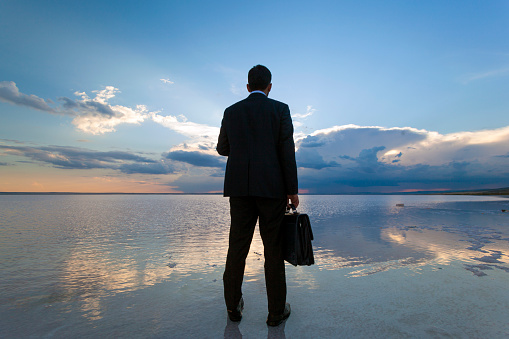Businessman looking away on salt lake at sunset