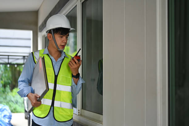 istock Engineer in safety helmet communicating with walkie talkie and checking building construction progress. 1455416189