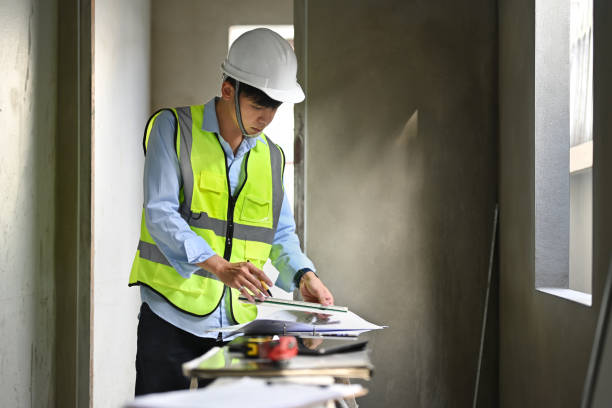 istock Engineer man in safety helmet working at blueprints and checking building construction progress at construction site. 1455416192