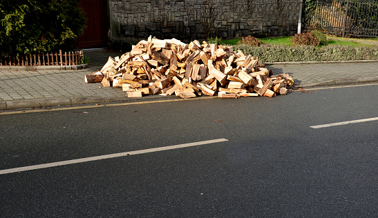 a pile of wood prepared near the sidewalk as fuel for a fireplace or for heating in a critical period of power outages. blackout saves chopped firewood even for the pizza oven, roadside, house, home, chopped wood