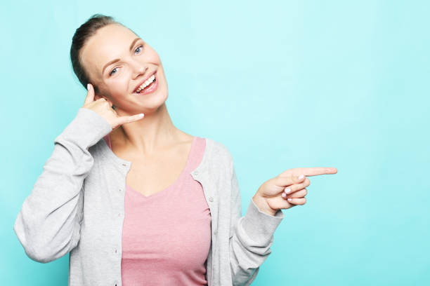 Smiling young woman pointing with finger at blank copy space aside stock photo