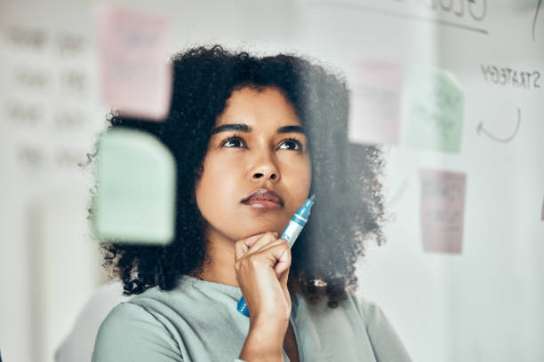 istock Thinking of marketing strategy on sticky note, post it paper for planning creative advertising idea and thinking of reminder on glass board. Business woman with plan for startup company at work 1455418942