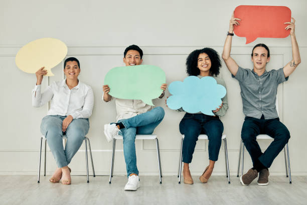 istock Diversity business people with speech bubble sign, banner or poster waiting for interview. Social media, chat or voice team of candidates together in line for job vacancy in the office with opinion 1455419451