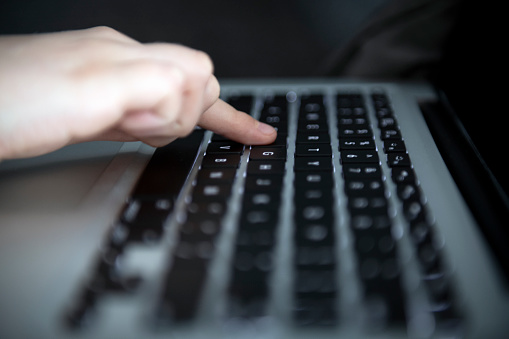 Defocused laptop keyboard with finger on on of the key