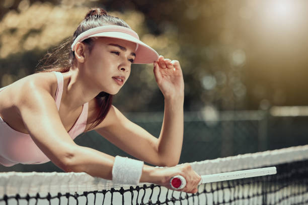 kobieta, tenisistka i zmęczona tenisistka trenująca z determinacją do fitnessu, ćwiczeń i letniego treningu na odkrytym korcie tenisowym. gra konkursowa, dziewczyna odpoczywająca na sieci i spragniony młody dorosły - tennis court sports training tennis net zdjęcia i obrazy z banku zdjęć