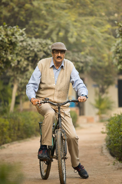 istock Happy old man riding bicycle on garden path 1455421109