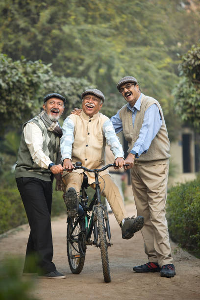 istock Ecstatic old man with friend learning to ride a bicycle at park 1455421355