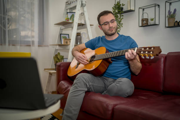 istock Young man playing a guitar at home 1455421490