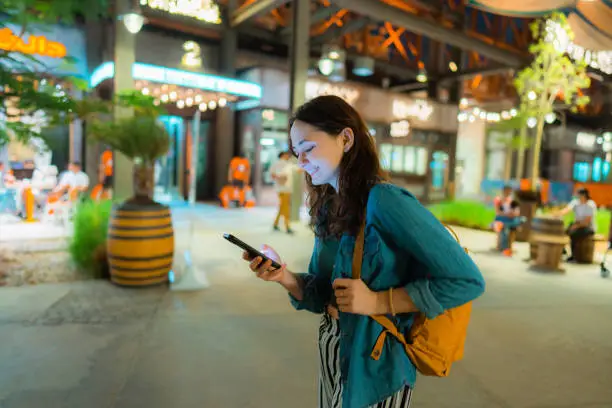 Photo of Woman walking in La Mer, Dubai  at night with smartphone