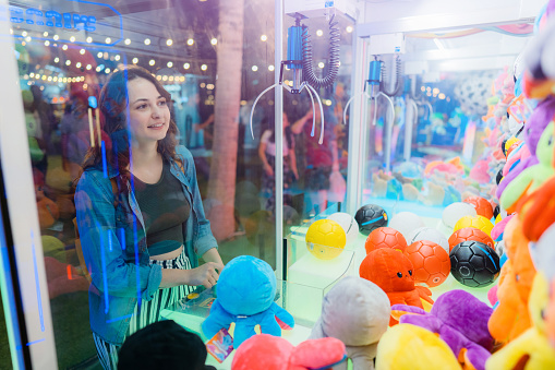 Young Caucasian woman playing on claw machine