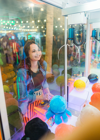 Young Caucasian woman playing on claw machine