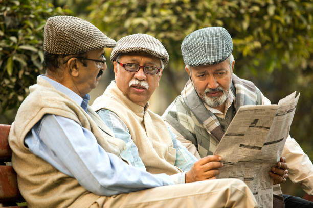 istock Older male friends reading newspaper at park 1455422580