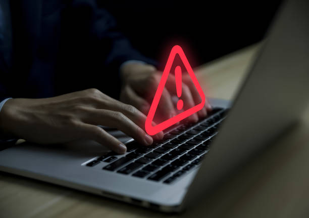 istock Businessman using laptop showing warning triangle and exclamation sign icon Warning of dangerous problems Server error. Virus. Maintenance concept. caution internet technology network security 1455422656