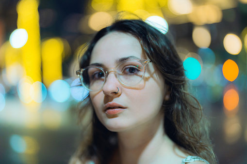 Portrait of young Caucasian woman in eyeglasses on the background of lights