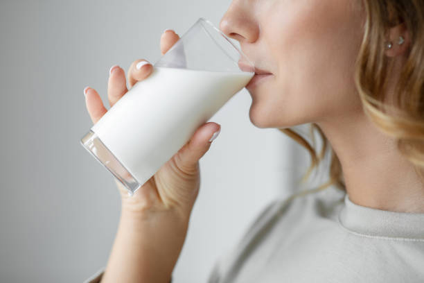 mujer bebiendo un vaso de leche - leche fotografías e imágenes de stock