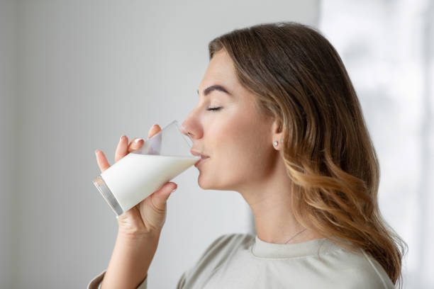 mujer bebiendo un vaso de leche - mujer bebiendo leche fotografías e imágenes de stock