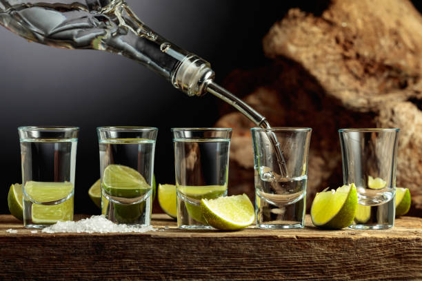 Silver Tequila with salt and lime slices on an old wooden board. stock photo